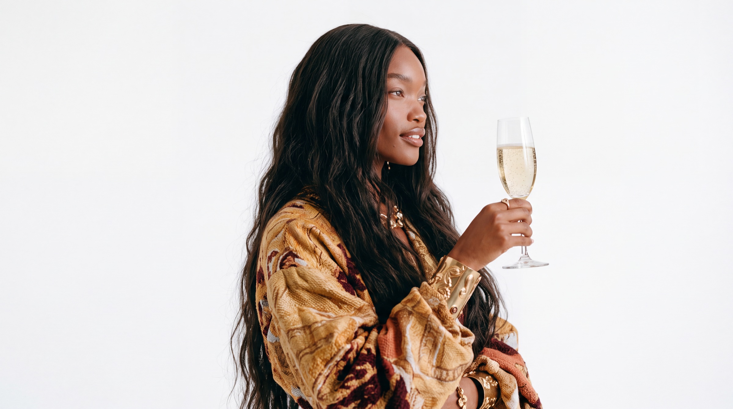 A woman in a printed silk jacket holding a flute of champagne