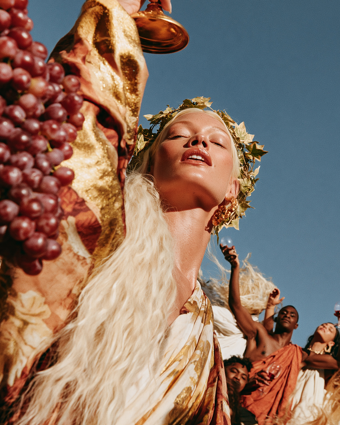 A guest in a gold laurel crown raising a cup to the sky
